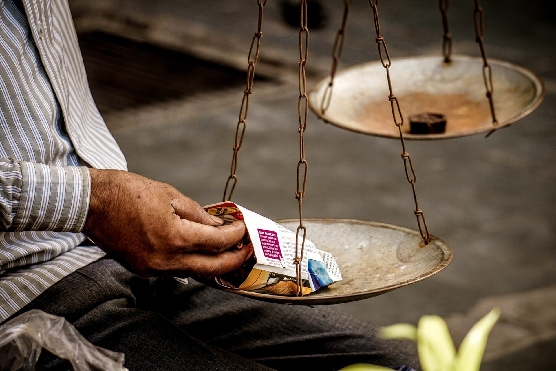 A trader balancing a traditional two-pan weighing scale